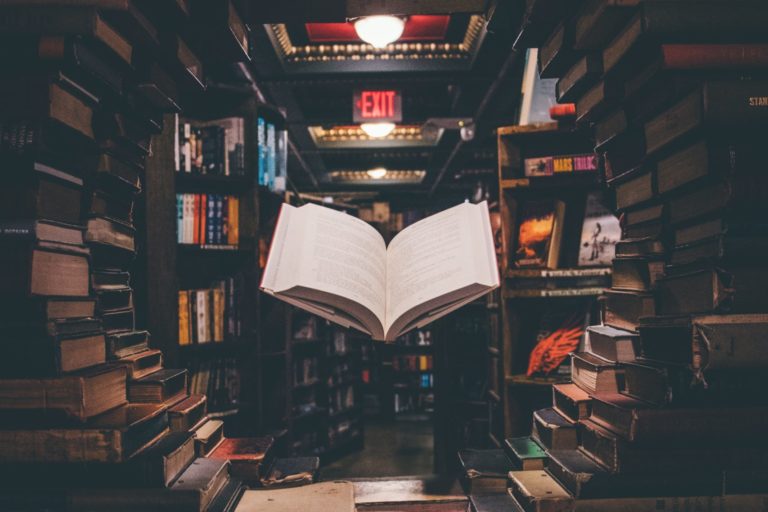 view of floating open book from stacked books in library