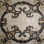 Mosaico de pedras com espirais em preto, branco e tons de terra