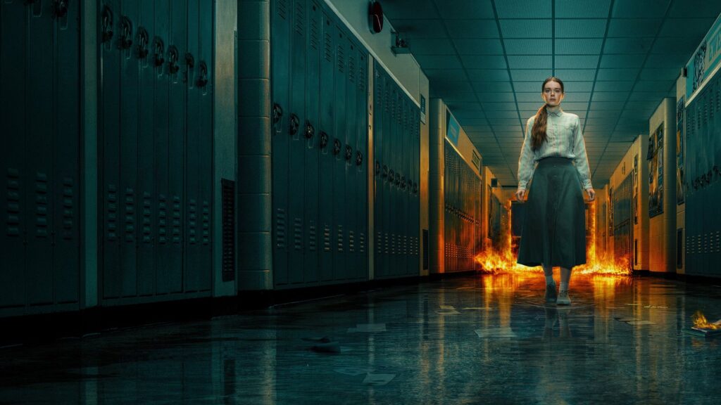 Carrie no corredor da escola com chamas no chão