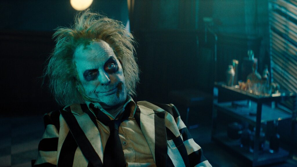 Beetlejuice de terno listrado e cabelo desgrenhado em Os Fantasmas Ainda se Divertem