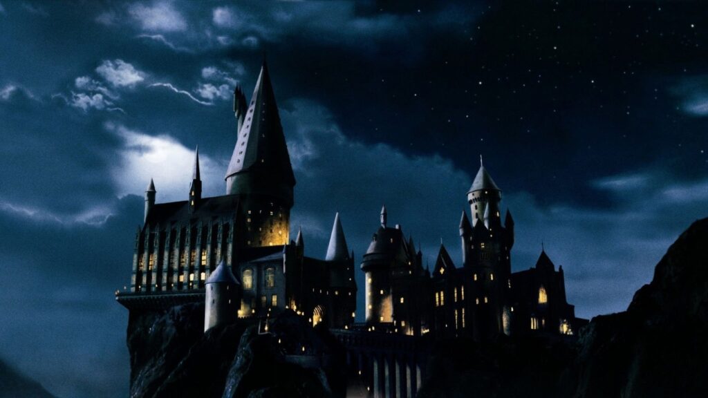 O castelo de Hogwarts à noite, sob um céu de nuvens e estrelas